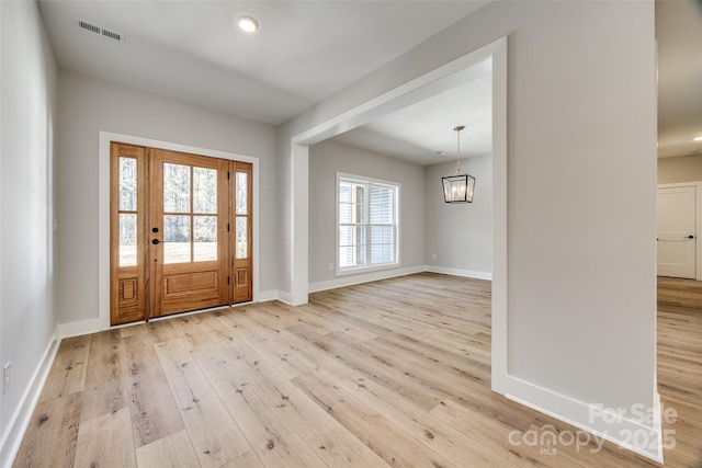 foyer entrance with a chandelier and light hardwood / wood-style floors