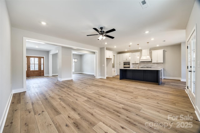 unfurnished living room featuring sink, ceiling fan, and light wood-type flooring