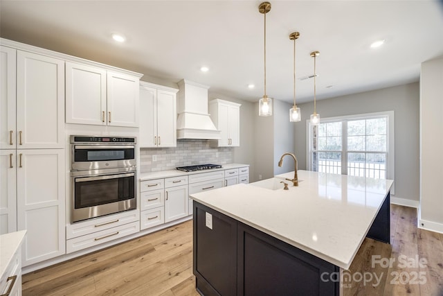 kitchen featuring white cabinetry, sink, hanging light fixtures, a kitchen island with sink, and stainless steel appliances