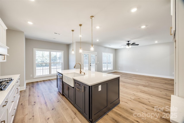 kitchen with sink, white cabinetry, decorative light fixtures, a center island with sink, and appliances with stainless steel finishes