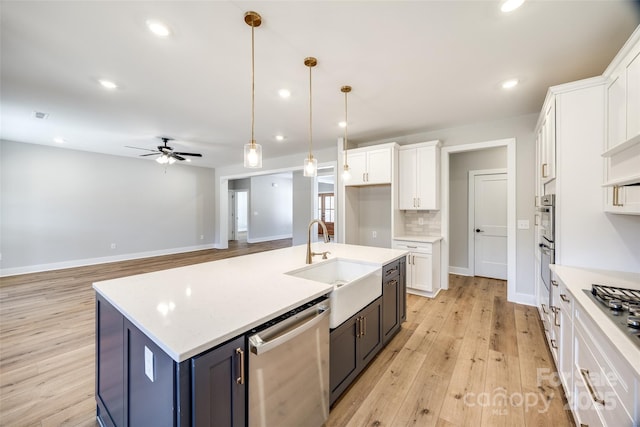 kitchen featuring appliances with stainless steel finishes, pendant lighting, tasteful backsplash, an island with sink, and white cabinets