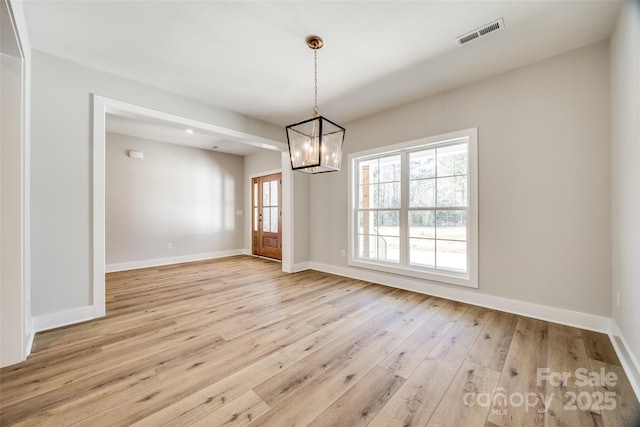 unfurnished dining area with an inviting chandelier, light hardwood / wood-style flooring, and a wealth of natural light