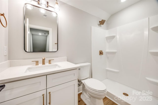 bathroom featuring hardwood / wood-style flooring, a shower, vanity, and toilet