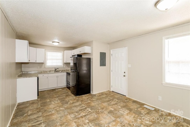 kitchen with black fridge, a textured ceiling, sink, white cabinets, and electric panel