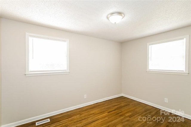 spare room featuring a wealth of natural light, a textured ceiling, and hardwood / wood-style flooring