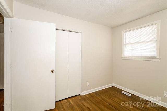 unfurnished bedroom featuring a closet and hardwood / wood-style flooring