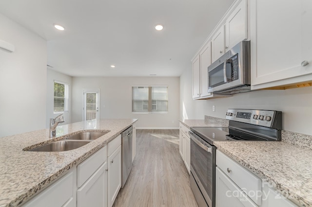 kitchen with white cabinets, sink, light stone countertops, light wood-type flooring, and stainless steel appliances