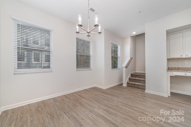 unfurnished dining area with light wood-type flooring and an inviting chandelier