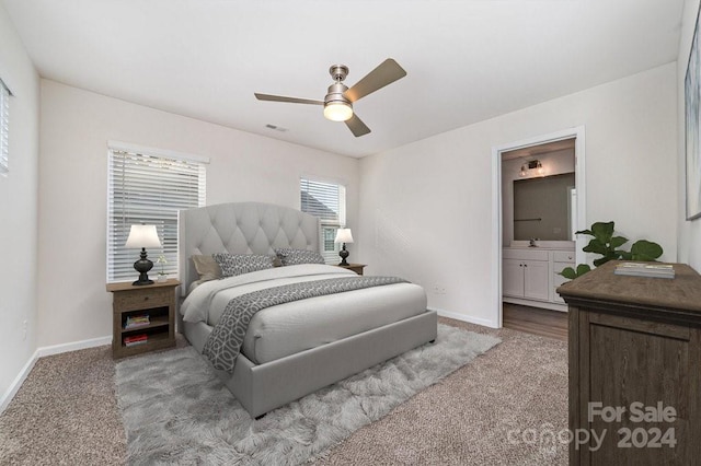 bedroom with ensuite bath, ceiling fan, sink, and light carpet