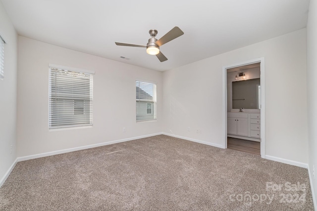 unfurnished bedroom with carpet flooring, ceiling fan, sink, and ensuite bathroom