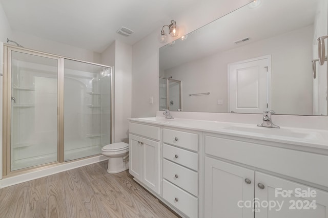 bathroom featuring hardwood / wood-style flooring, vanity, toilet, and a shower with shower door