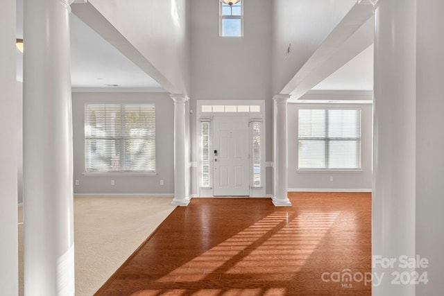 foyer with crown molding, plenty of natural light, a high ceiling, and hardwood / wood-style flooring