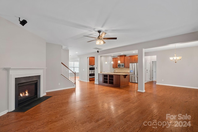 unfurnished living room with ceiling fan with notable chandelier, dark hardwood / wood-style flooring, and sink