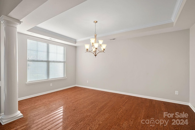 empty room featuring a raised ceiling, crown molding, hardwood / wood-style floors, and an inviting chandelier