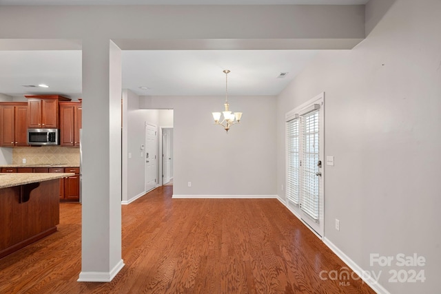 interior space featuring wood-type flooring, tasteful backsplash, and a notable chandelier