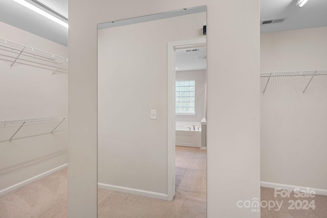 walk in closet featuring light carpet