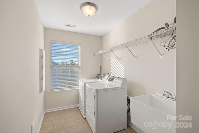 laundry room featuring washing machine and dryer, sink, and light tile patterned floors