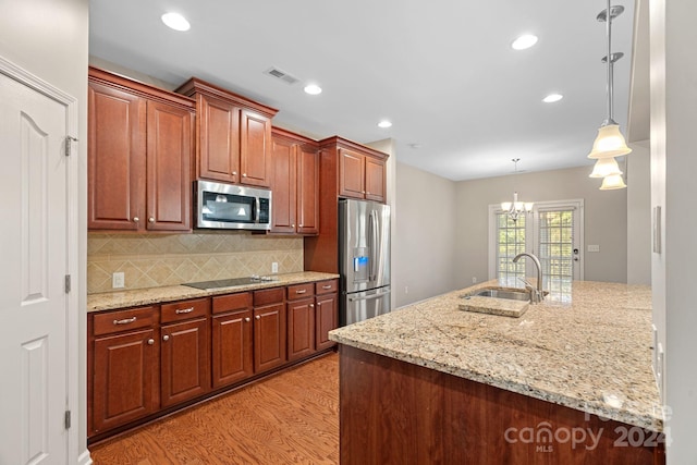 kitchen featuring pendant lighting, sink, light wood-type flooring, stainless steel appliances, and a chandelier