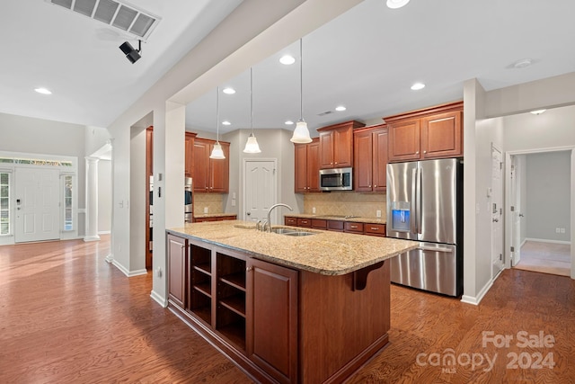 kitchen with light stone countertops, decorative backsplash, sink, and stainless steel appliances