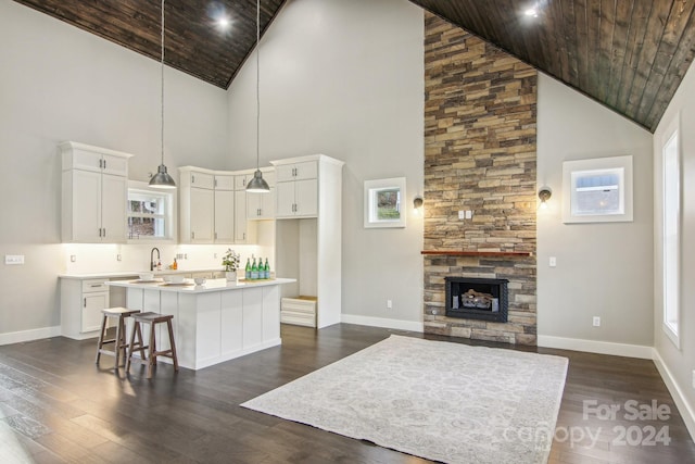 kitchen with white cabinets, a kitchen island, wood ceiling, and high vaulted ceiling