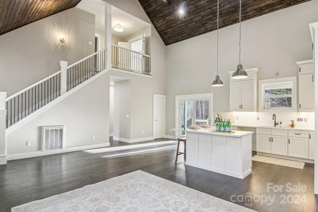 kitchen featuring dark hardwood / wood-style floors, a center island, hanging light fixtures, and high vaulted ceiling