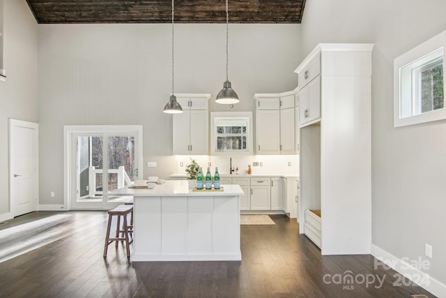 kitchen with a wealth of natural light, hanging light fixtures, and dark wood-type flooring