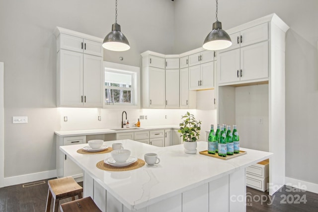 kitchen with white cabinets, decorative light fixtures, a kitchen island, and sink