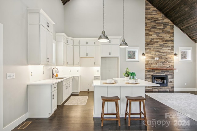 kitchen featuring sink, decorative light fixtures, high vaulted ceiling, white cabinets, and a kitchen island