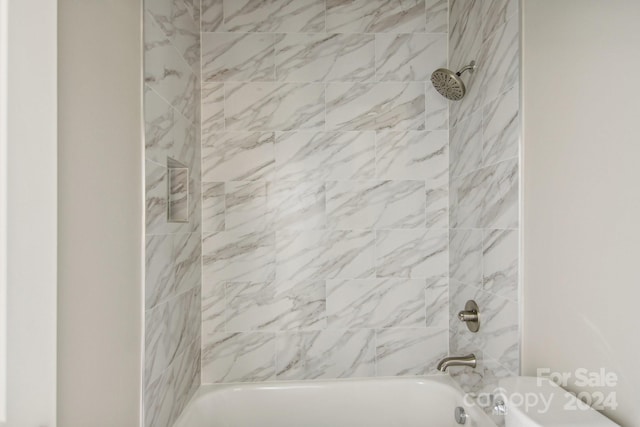 bathroom with toilet and tiled shower / bath