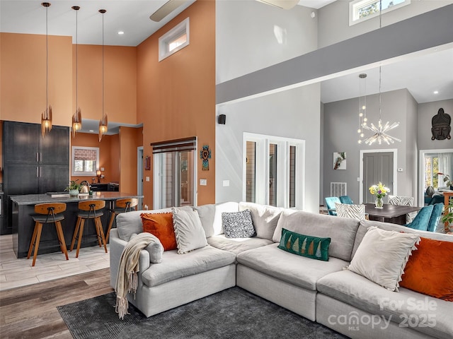 living room with a notable chandelier, hardwood / wood-style flooring, and a high ceiling