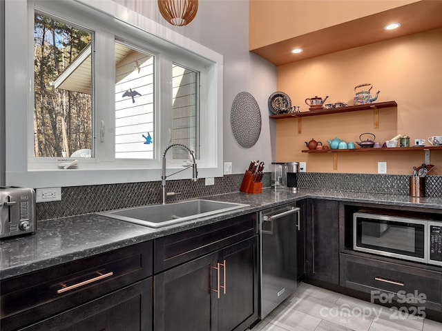 kitchen featuring stainless steel appliances, light tile patterned flooring, sink, and dark stone countertops