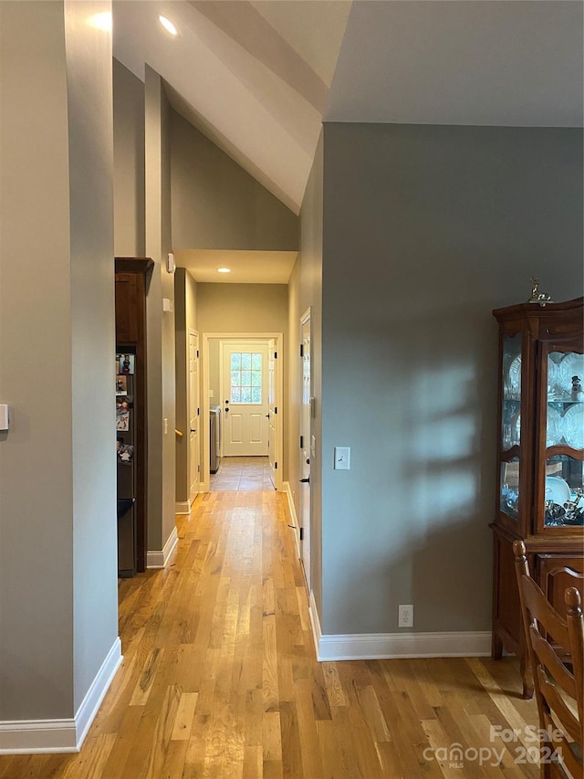 hallway featuring light hardwood / wood-style floors and high vaulted ceiling