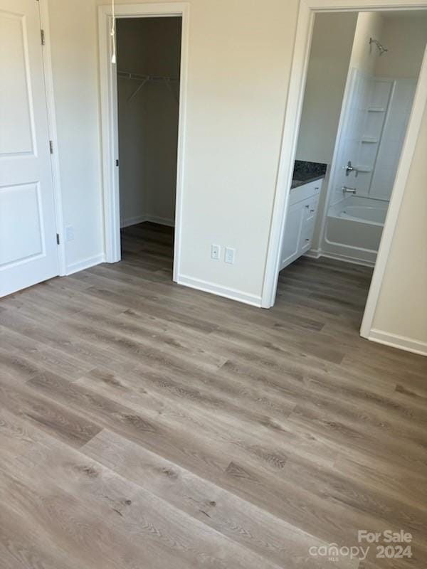 unfurnished bedroom with a closet, light hardwood / wood-style flooring, ensuite bath, and a spacious closet