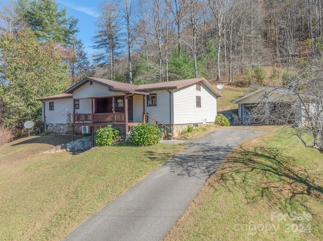 view of front of house with a front yard, a porch, a garage, and an outdoor structure