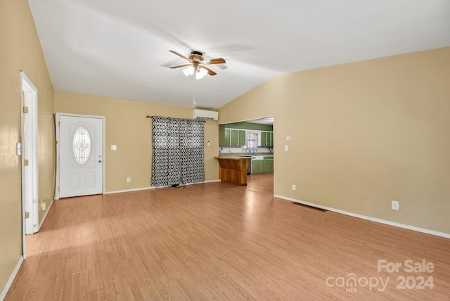 unfurnished living room with lofted ceiling, ceiling fan, light wood-type flooring, and an AC wall unit