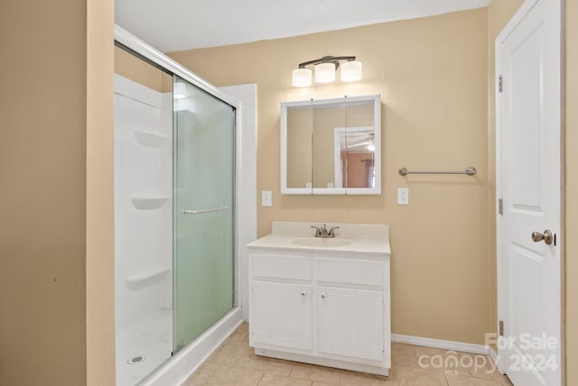 bathroom with tile patterned flooring, vanity, and walk in shower