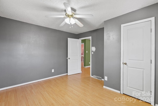 unfurnished bedroom with a textured ceiling, light wood-type flooring, and ceiling fan