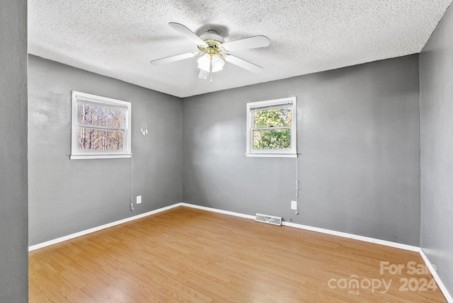 unfurnished room featuring hardwood / wood-style flooring, ceiling fan, and a textured ceiling