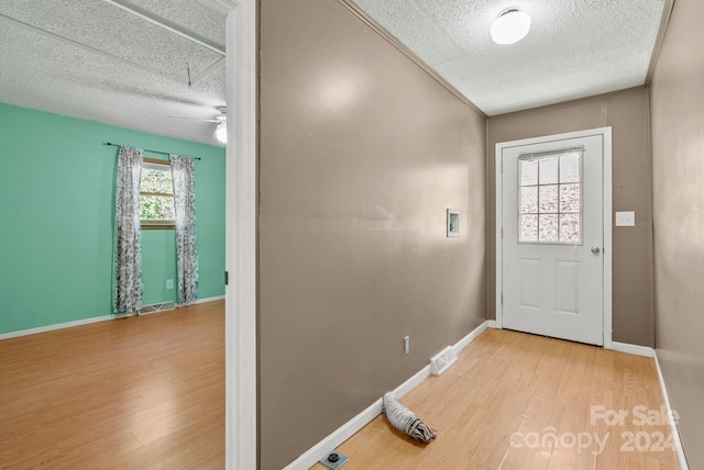 doorway to outside featuring a textured ceiling, light wood-type flooring, and ceiling fan