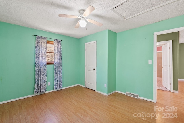 unfurnished bedroom with ceiling fan, wood-type flooring, and a textured ceiling