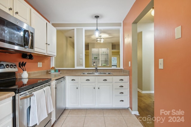 kitchen featuring appliances with stainless steel finishes, decorative light fixtures, white cabinetry, and sink