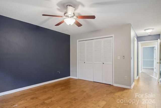 unfurnished bedroom featuring ceiling fan, a closet, and light wood-type flooring