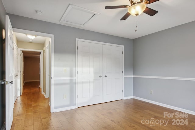 unfurnished bedroom featuring ceiling fan, a closet, and light wood-type flooring