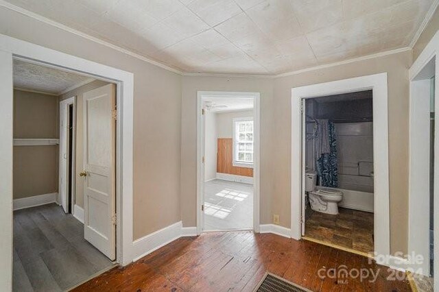 corridor with dark hardwood / wood-style flooring and crown molding