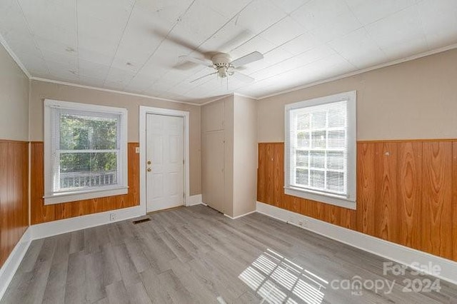 spare room featuring plenty of natural light, ornamental molding, and light hardwood / wood-style flooring