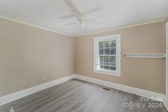 empty room featuring wood-type flooring, a textured ceiling, and ornamental molding