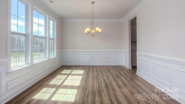 unfurnished dining area featuring plenty of natural light, crown molding, dark wood-type flooring, and a chandelier