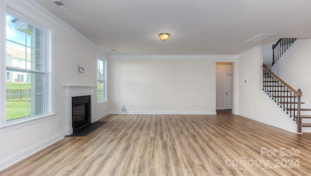 unfurnished living room featuring light hardwood / wood-style floors, crown molding, and a healthy amount of sunlight