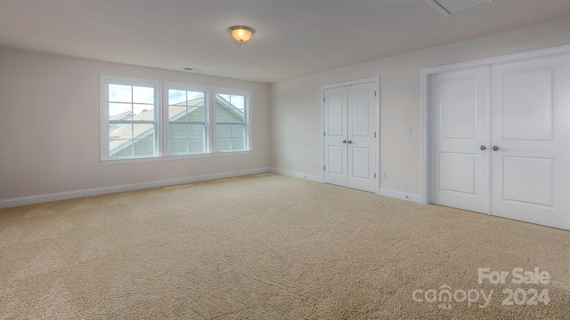 unfurnished bedroom featuring carpet and two closets