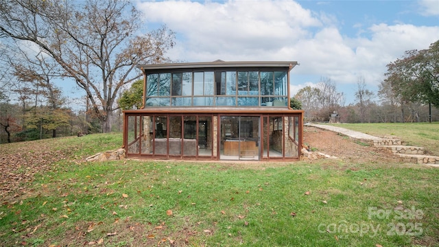 rear view of house featuring a yard and a sunroom